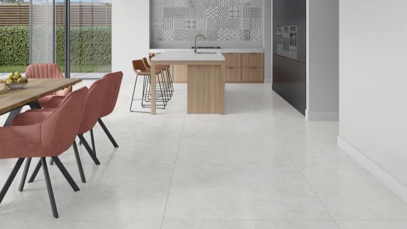 cozinha e sala de jantar em conceito aberto com chão revestido de porcelanato branco, bancada de madeira, mesa de madeira, banquetas e cadeiras com estofado rosa