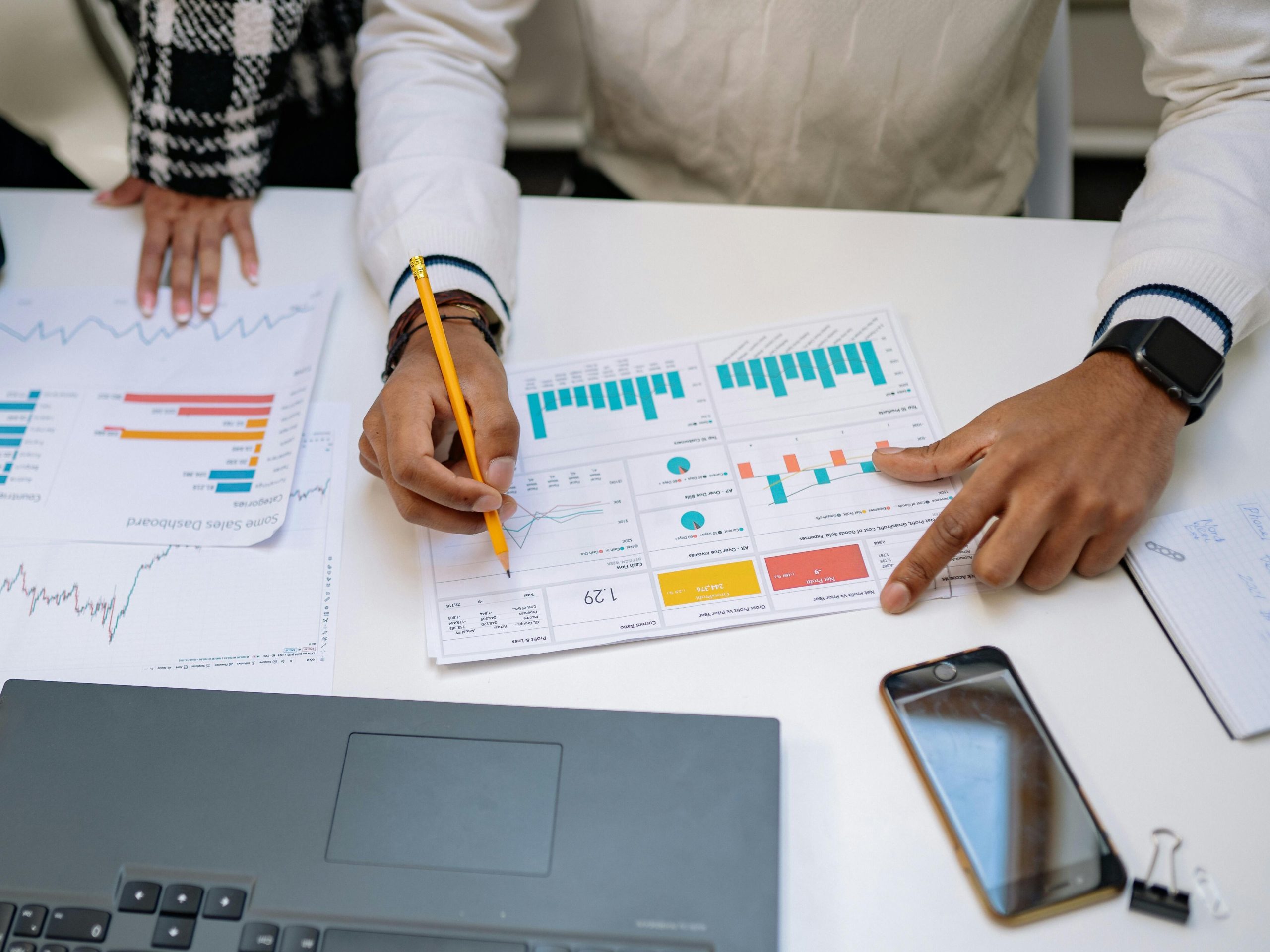 Pessoa analisando gráficos e dados em mesa de trabalho