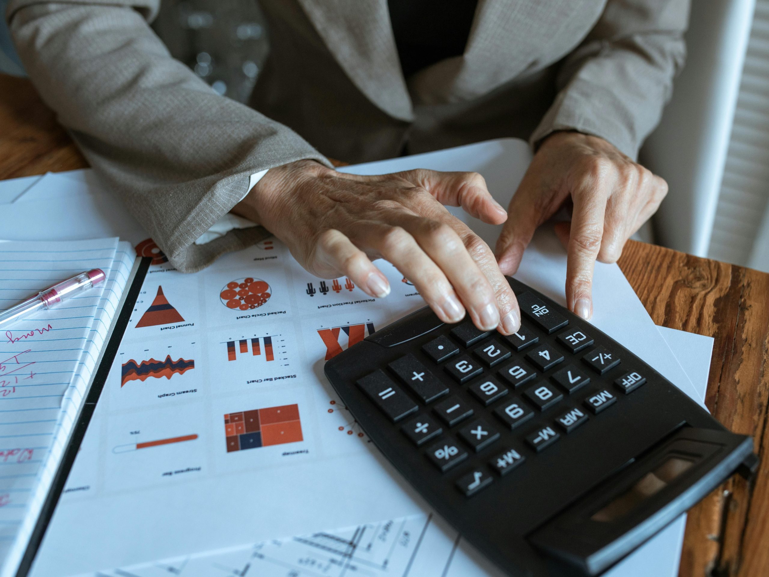 Pessoa usando calculadora com gráficos ao fundo