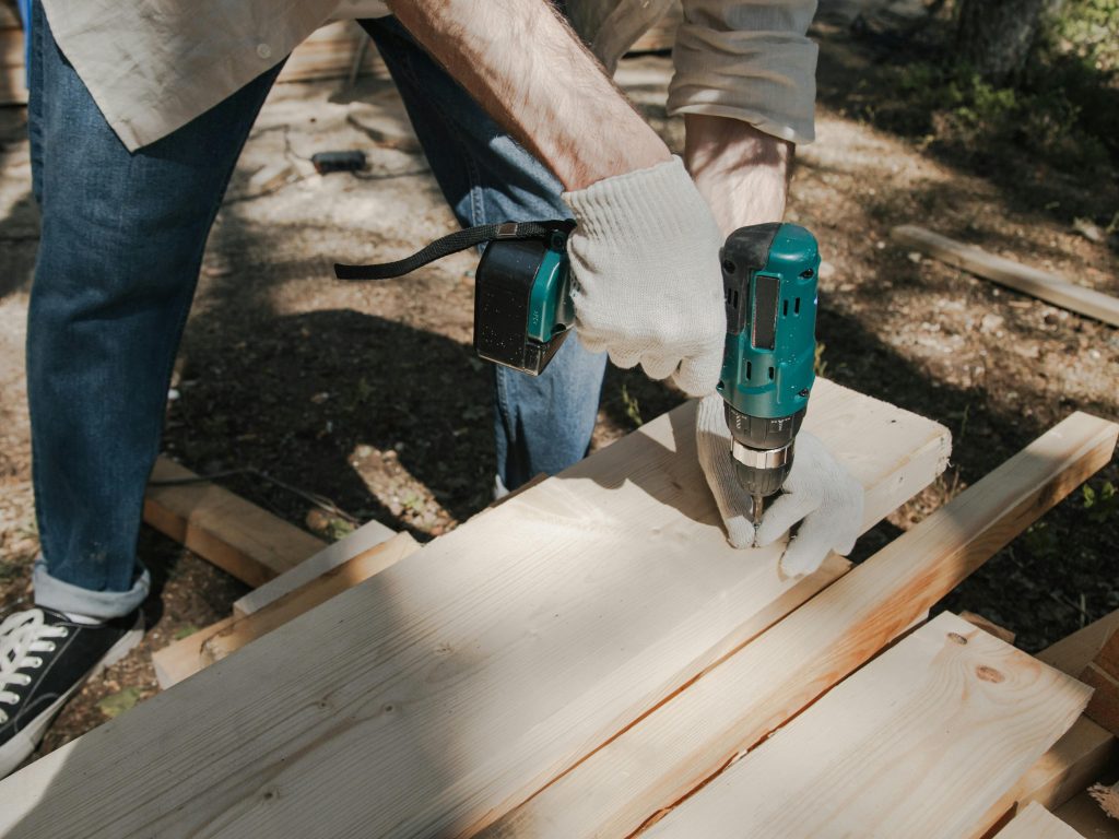 Homem usando furadeira em madeira ao ar livre