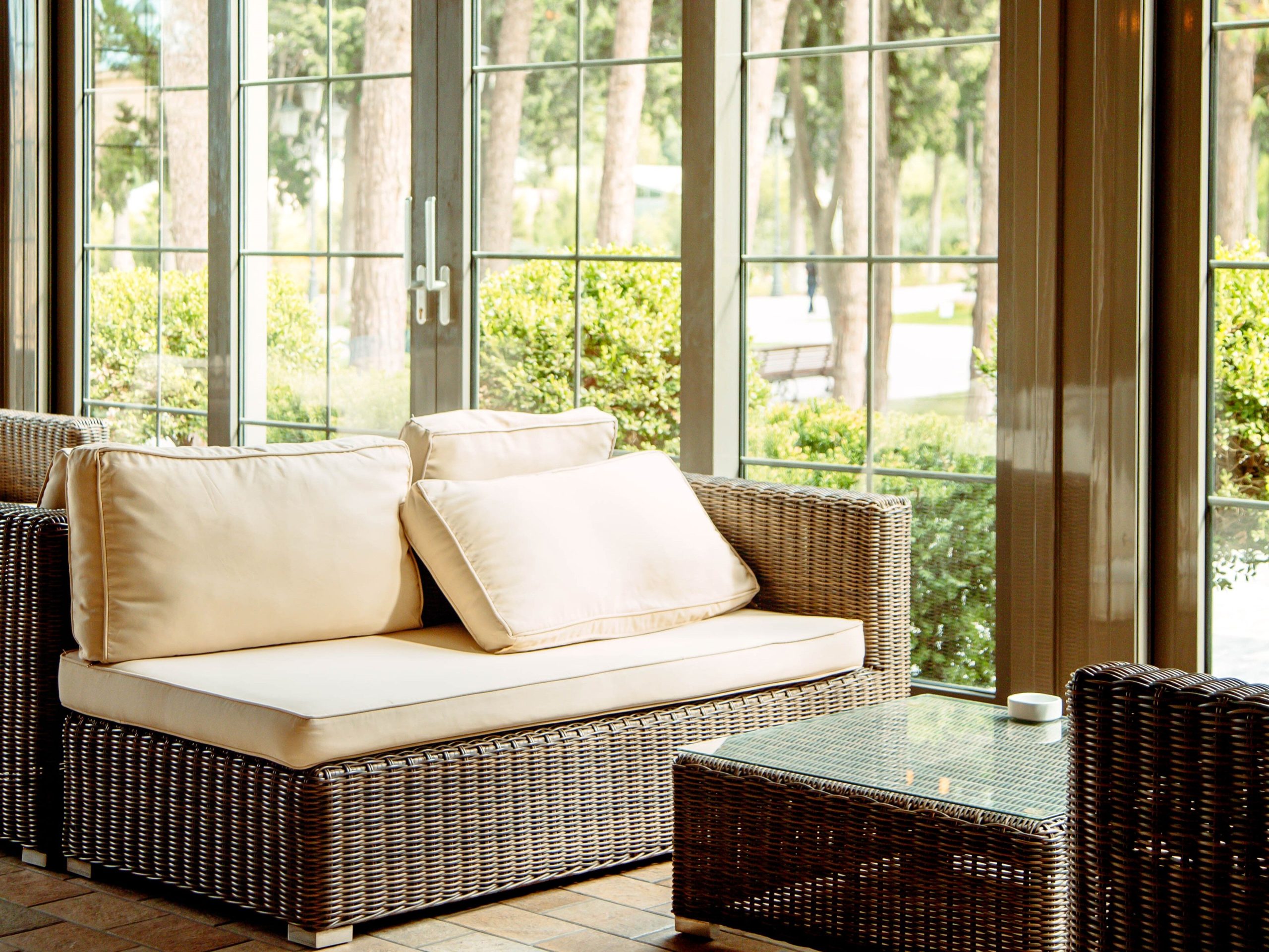 sofa-ao-ar-livre-com-almofadas-bege-e-mesa-de-cafe-em-frente-a-janela-restaurante.jpg