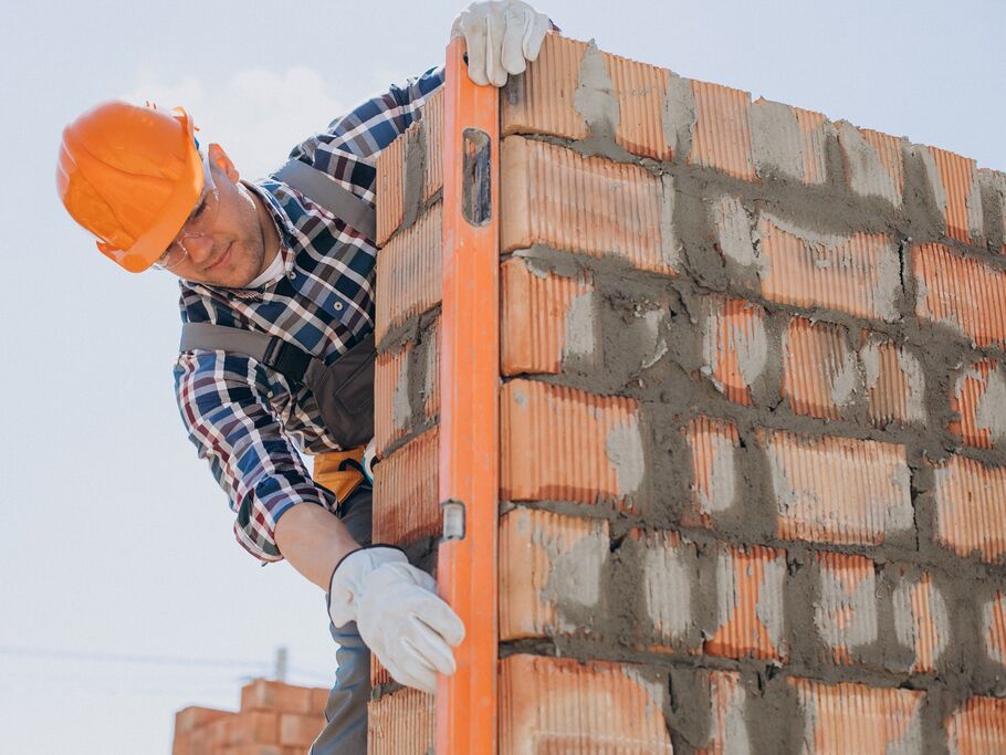 Homem em construção ajustando alvenaria com nível
