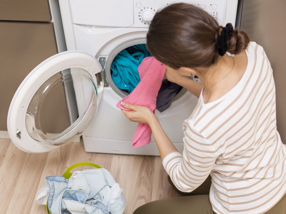 Mulher colocando roupas na máquina de lavar