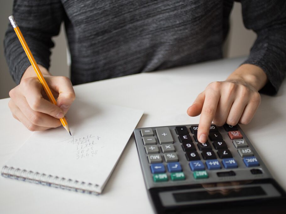 Pessoa calculando com lápis e calculadora.