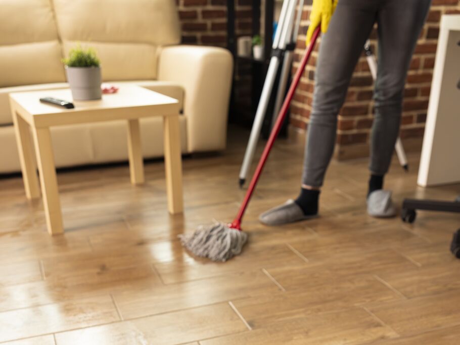 Pessoa limpando o chão com mop em sala de estar.