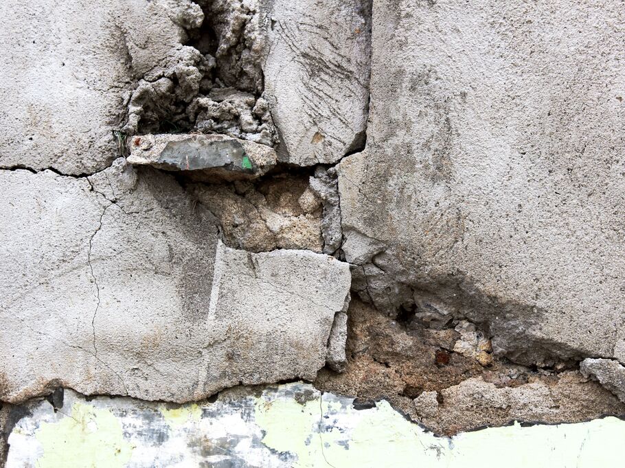 Pintura descascada e rachaduras na parede de concreto