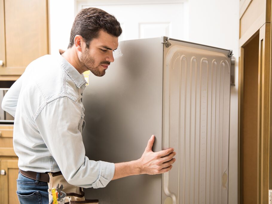 Homem ajustando geladeira em cozinha moderna