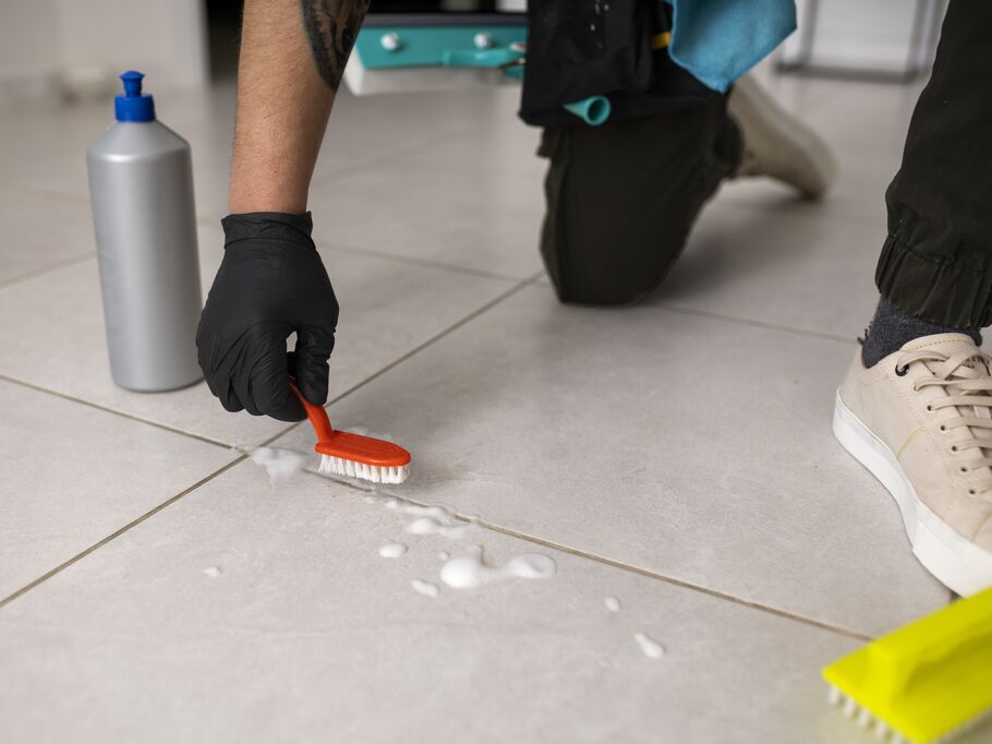 Pessoa limpando piso com escova e produtos de limpeza