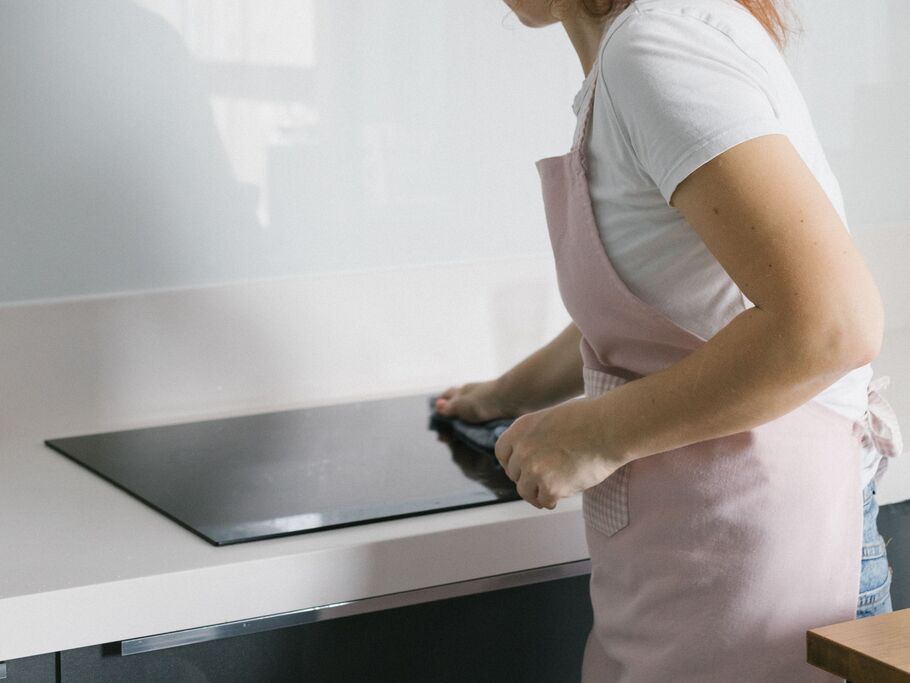 Mulher limpando fogão na cozinha moderna